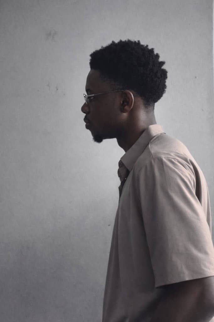 Portrait of Inioluwa Badairo in profile with glasses and a light shirt.